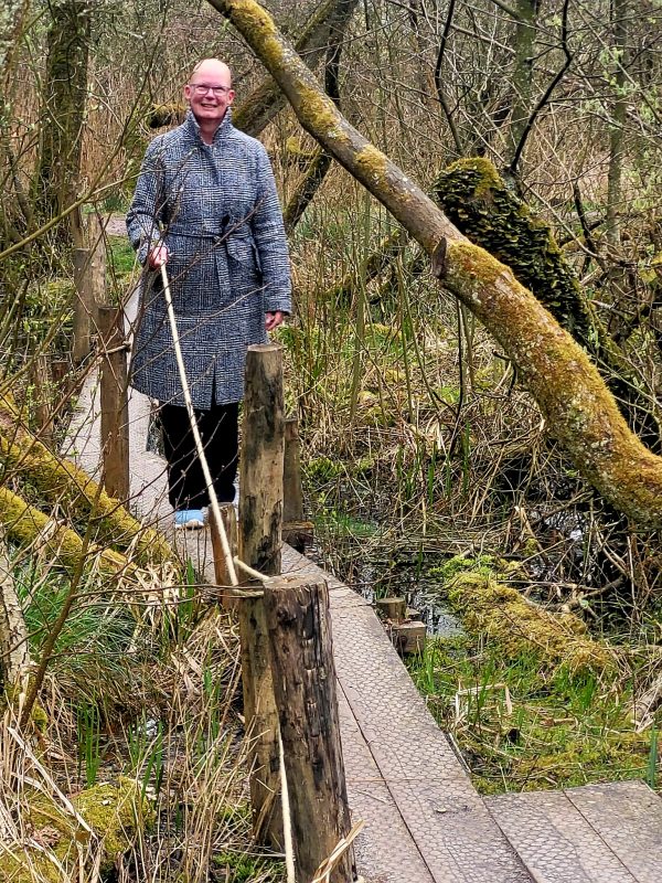 Over een smalle boardwalk lopen met een touw als houvast, balans tussen zekerheid en nieuwe ervaringen